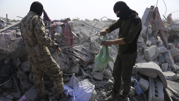 People look at a destroyed houses near the village of Barisha, in Idlib province, Syria after an operation by the US military that targeted Abu Bakr al-Baghdadi. 