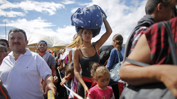 A Venezuelan woman carries a bundle on her head across the border into Colombia.