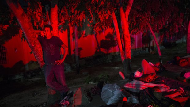 A man stands among other migrants while waiting for a ride on the side of the road, as a caravan of Central Americans continues its slow march towards the US border near Tapanatepec, Mexico.