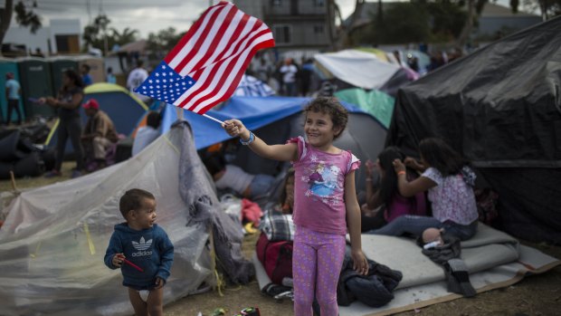 Seven-year-old Honduran migrant Genesis Belen Mejia Flores waves an American flag at US border in Tijuana, Mexico.