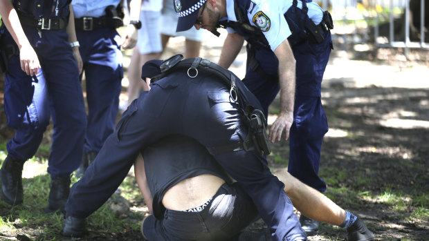 Police outside Field Day attempt to make a man open his mouth.