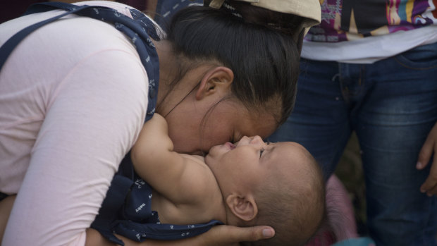 Daisy Zuniga, a migrant from Honduras, plays with her baby Glinder in a shelter in Chiquimula, Guatemala. They are part of a group walking toward the US.