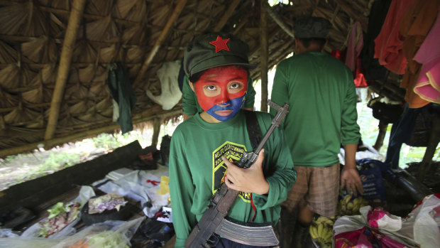 A woman New People's Army guerrilla with her face painted to conceal her identity holds her firearm inside a shelter at a rebel encampment tucked in the harsh wilderness of the Sierra Madre mountains, south-east of Manila, Philippines.
