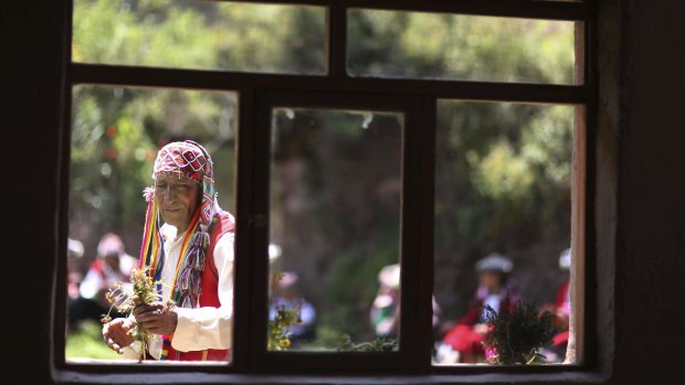 A farmer who now sells Andean clothes collects flowers while he waits for tourists who have come to see Rainbow Mountain, in Pitumarca, Peru.