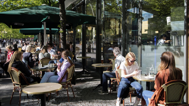People sit at tables outside a cafe at Kungstradgarden in Stockholm, Sweden.