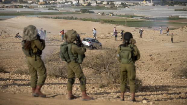 Palestinians and Israeli activists run away from tear gas fired by Israeli soldiers during a demonstration against the construction of Jewish settlements in the Jordan Valley.