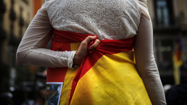 A woman holds a Spanish flag around her body during a ceremony marking the first anniversary of a terror attack in Las Ramblas promenade in Barcelona, Spain.