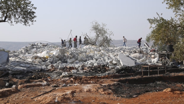 People look at destroyed houses near the village of Barisha, Idlib province, Syria.