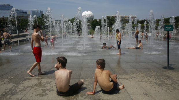 Children play and cool off in the fountain of Andre Citroen square in Paris.