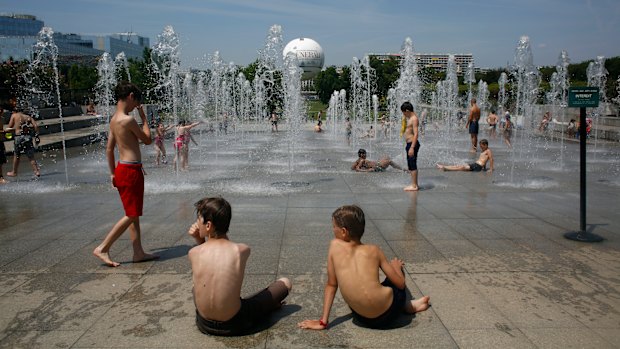 Children play and cool off in the fountain of Andre Citroen square in Paris.