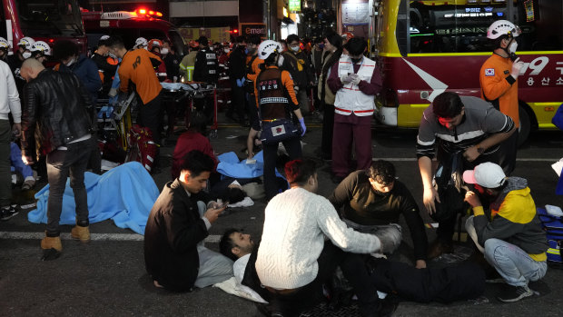 Rescue workers and firefighters try to help injured people near the scene on Saturday night.