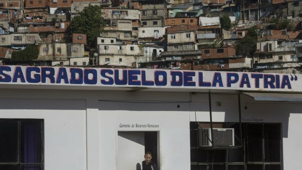 The Spanish phrase "Sacred soil of the fatherland" covers an administrative office at a wholesale food market, near a shantytown in Caracas, Venezuela.