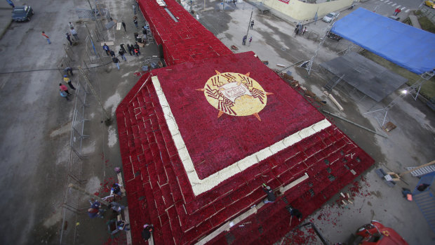 People place roses on a structure made to resemble the Cochasqui pyramid temple as they try to impose a new category in the Guinness World Records as the biggest structure made with roses, in Tabacundo, Ecuador.