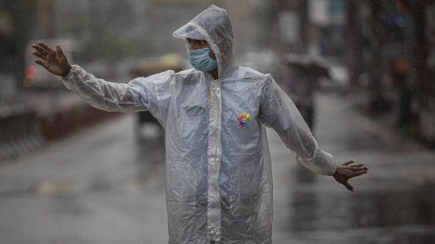 An Indian traffic police person controls traffic during heavy rain in Gauhati, India.