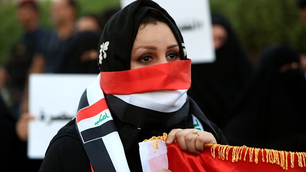 An Iraqi woman covers her face with the national flag as she participates in a demonstration demanding better public services and jobs in the southern city of Basra, Iraq, last week. 