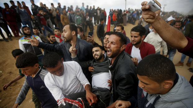 Palestinian protesters evacuate a wounded youth during clashes with Israeli troops along the Gaza Strip border with Israel, on Friday.