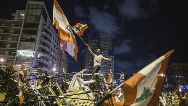 An anti-government protester waves a Lebanese flag as he stands on top of a pile of broken tents in Martyrs' Square, Beirut, on October 29.