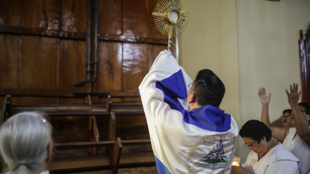 Father Harvey Padilla exposes the consecrated host to one of the barricaded doors of the San Juan Bautista Church after supporters of President Daniel Ortega attempted to enter the church by force.