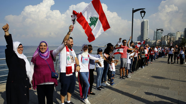 Anti-government protesters form a human chain as a symbol of unity, during ongoing protests against the Lebanese government, on the Mediterranean waterfront promenade, in Beirut, Lebanon.