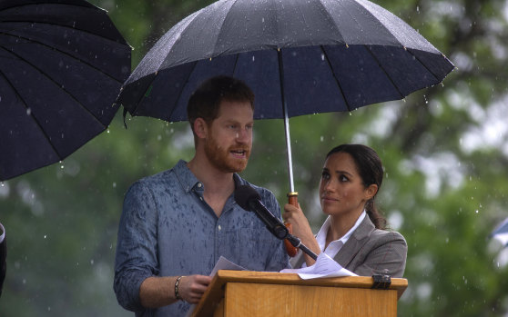 Under cover: Harry and Meghan take shelter at a community picnic at Dubbo in 2018. 