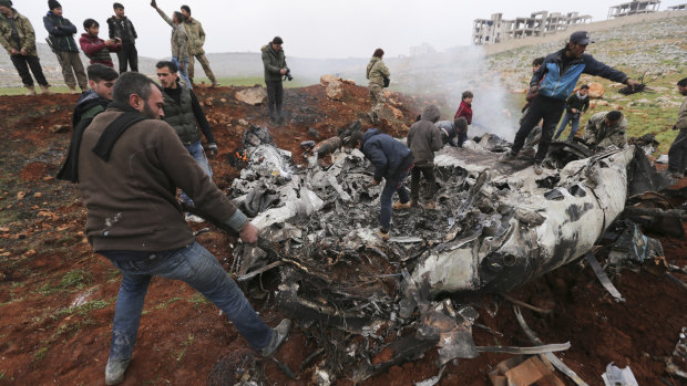 Syrians gather around a wreckage of a government military helicopter that was shot down in the countryside west of the city of Aleppo.