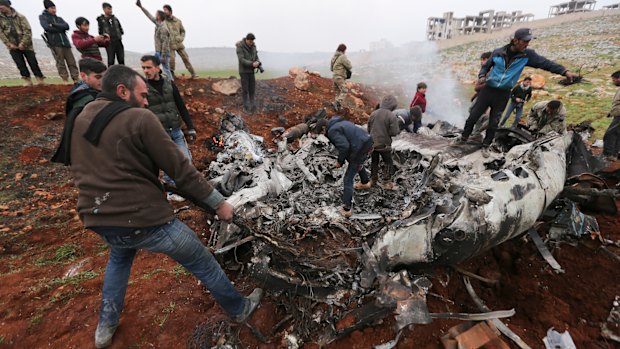 Syrians gather around a wreckage of a government military helicopter that was shot down in the countryside west of the city of Aleppo.