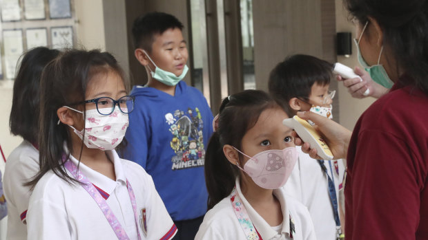 Staff members check students' body temperatures upon their arrival at Jakarta Nanyang School in Serpong on the outskirts of Jakarta, Indonesia.