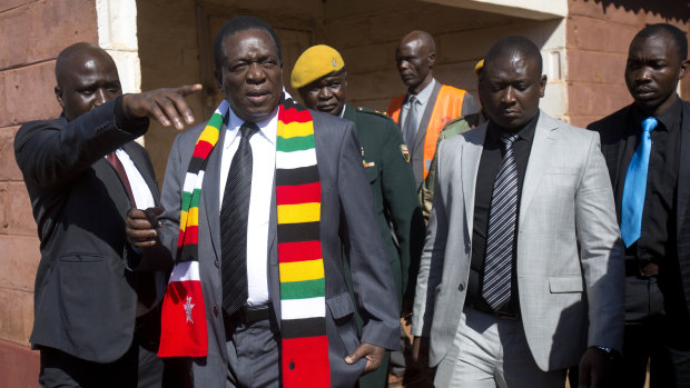 Zimbabwean President Emmerson Mnangagwa, in a scarf, leaves the polling station after casting his vote in Kwekwe.