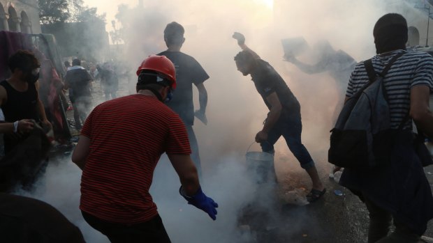 Anti-government protesters run to take cover while Iraqi Security forces fire tear gas during a demonstration in Tahrir Square in Baghdad on Iraq.