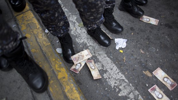 One hundred Bolivar bills lay on the ground close to the boots of several police officers, after they were thrown by protesters during a protest against the government of President Nicolas Maduro, in Caracas, Venezuela.