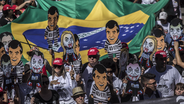 Demonstrators hold banners depicting local politicians during a rally against local government officials and in support of Brazil's former president Lula, now jailed.