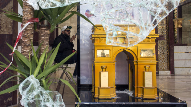 A replica of the Arc de Triomphe is pictured through the smashed window of a perfumery the day after riots erupted on the Champs Elysee.
