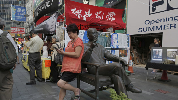 A woman plays on her phone next to a statue of the late Chinese Nobel Peace laureate Liu Xiaobo in Hong Kong.