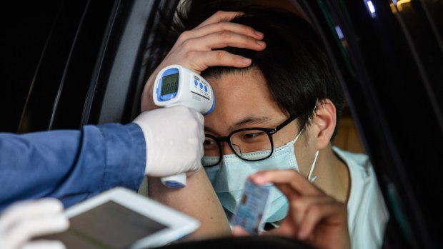 A man has his temperature taken at a drive through COVID-19 testing centre at Vibhavadi Hospital in Bangkok, Thailand.