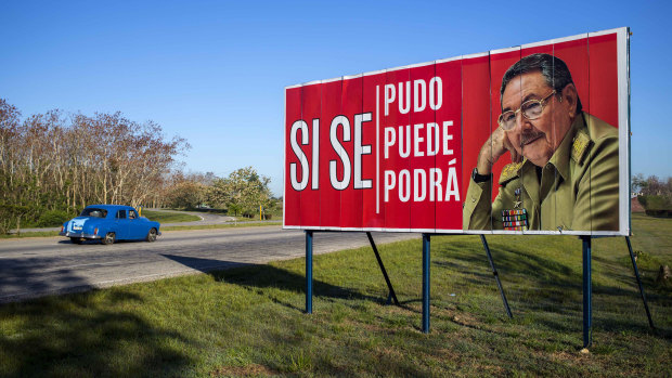 A car drives by a billboard that reads in Spanish “Yes we could, yes we can, yes we will” alongside a picture of Cuban President Raul Castro on the outskirts of Havana, Cuba.