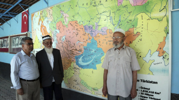 Uighur Muslim men stand in front of map showing the area claimed by Uighur separatists as “East Turkistan” marked in blue at a resettlement community in Kayseri in central Turkey. 