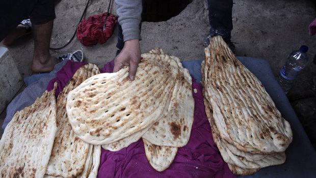 An Afghan man makes traditional bread at a makeshift camp for refugees and migrants in Lesvos.