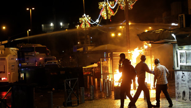 An Israeli police water cannon is deployed near the Damascus Gate to the Old City of Jerusalem as a fire burns during clashes between police and Palestinian protesters on Monday.