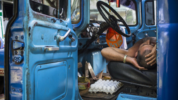 A truck driver takes a nap in the cabin of his truck at an outdoor food market in Havana, Cuba, on Saturday.