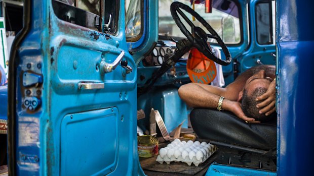 A truck driver takes a nap in the cabin of his truck at an outdoor food market in Havana, Cuba, on Saturday.