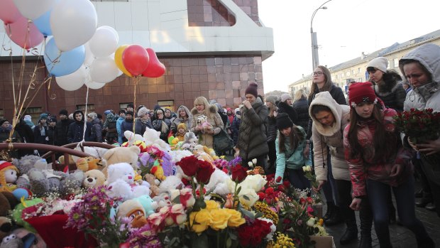 People lay flowers for the victims of Sunday's fire in a multi-story shopping centre.