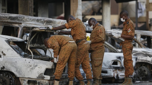 Soldiers examine burnt-out cars outside the Splendid Hotel in Ouagadougou, Burkina Faso, in 2016.