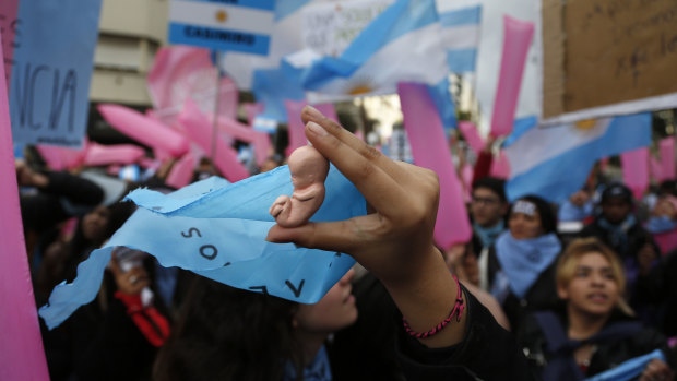 Pro-life youths, one holding a tiny featus figurine, protest against the proposed law in Buenos Aires.