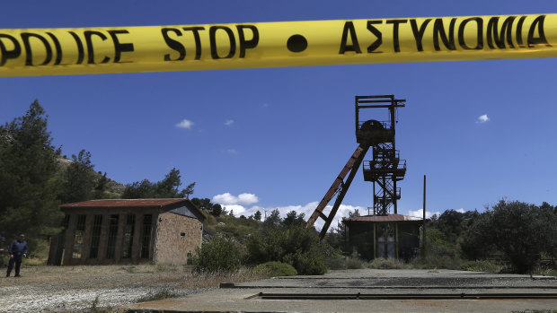 A Cypriot police office stands near the flooded mineshaft where two female bodies were found in April.