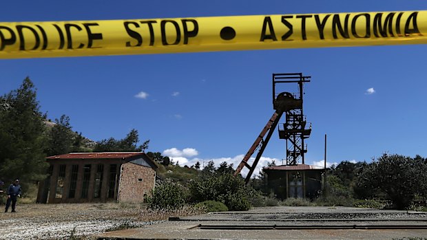 A Cypriot police office stands near the flooded mineshaft where two female bodies were found in April.