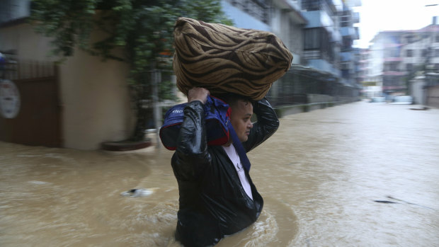 A Nepalese man wades with his belonging through a flooded street in Kathmandu, Nepal.