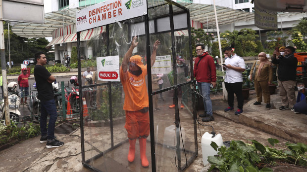 A government worker stands inside a makeshift sterilisation chamber in hopes of reducing the spread of the coronavirus in Jakarta.