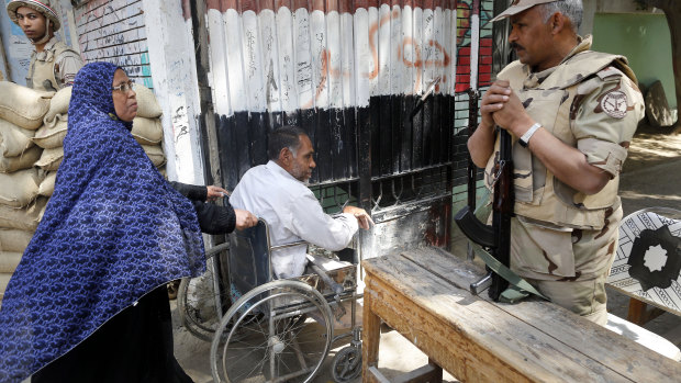 Army officers secure a Cairo polling station as people enter to vote on constitutional amendments on Sunday.