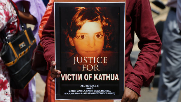 A woman holds a poster with a portrait of an eight-year-old girl who was kidnapped, raped and murdered.