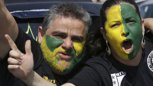 With their faces painted with the colours of Brazil, demonstrators shout slogans during a race in support of Jair Bolsonaro.